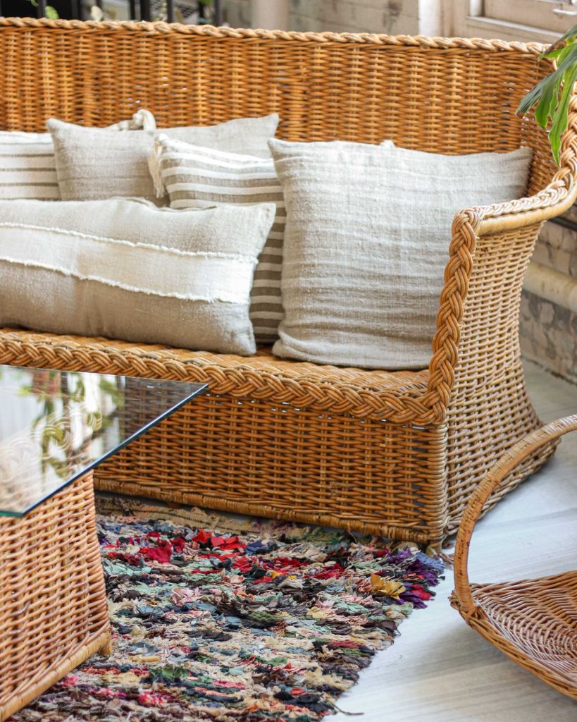 cosy brown natural wicker rattan sofa with soft cloth cushions in an indoor setting